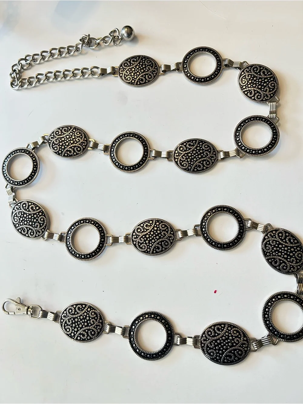 Silver-tone chain belt features textured medallion links and a hook closure L/XL